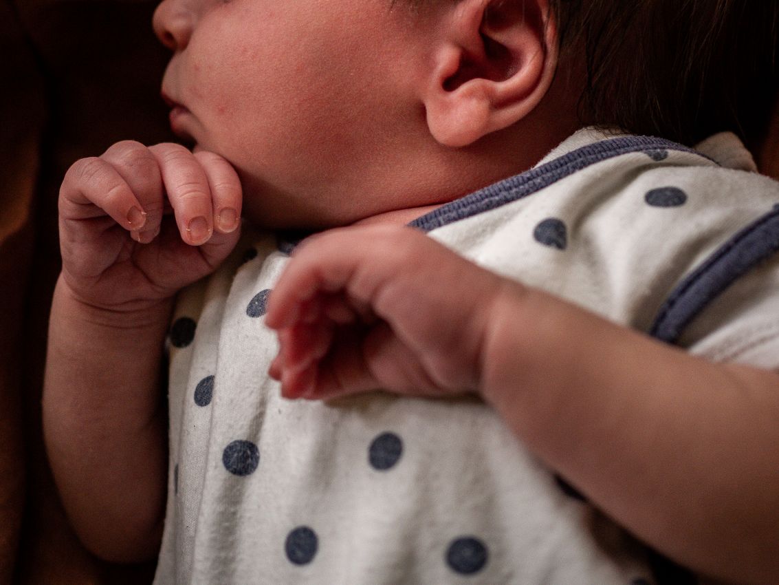 Newborn Shooting Detailaufnahme der Hände eines Neugeborenen in weiß blau gepunktetem Strampler